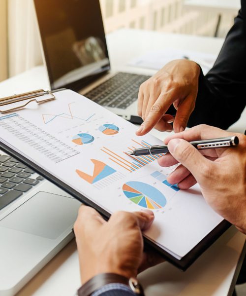 Business concept. Business people discussing the charts and graphs showing the results of their successful teamwork. Selective focus.